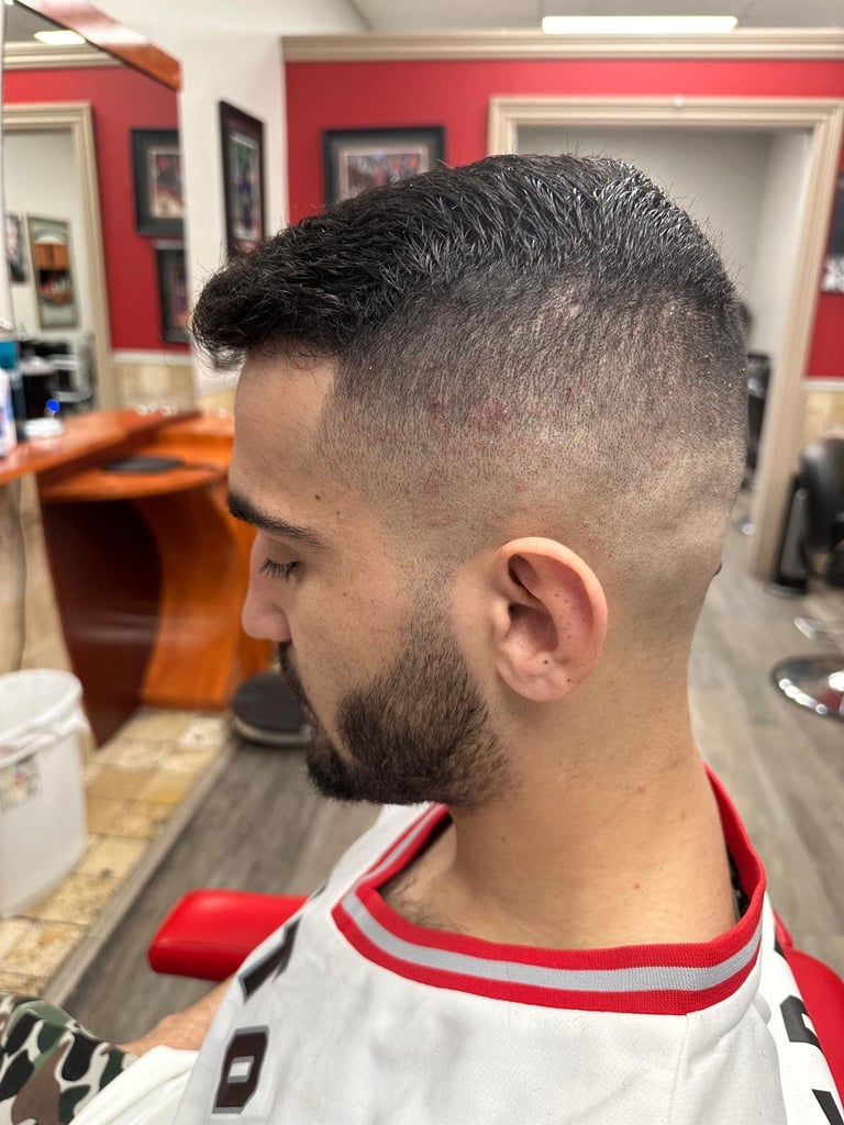 Man with short fade haircut and beard in a barber shop with red and white walls