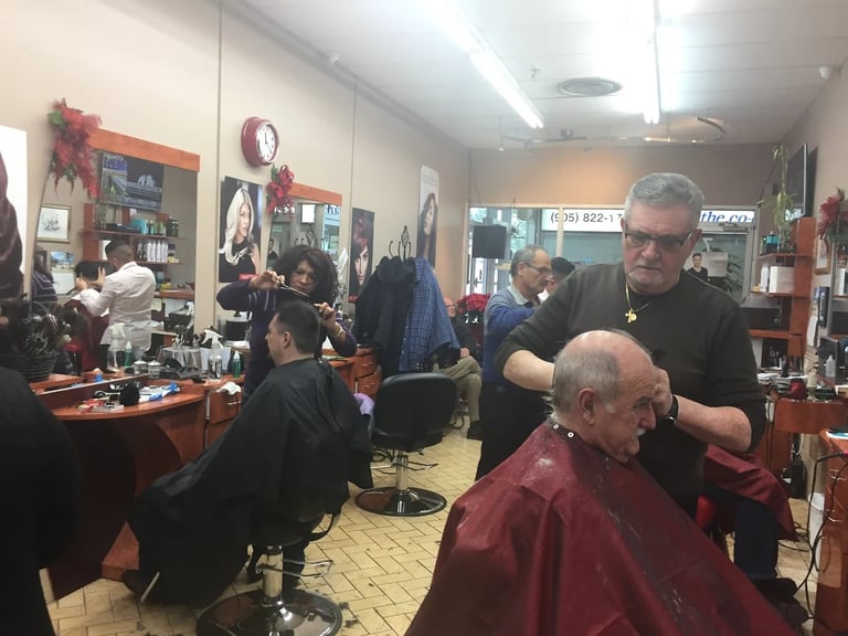A barber shop interior with staff cutting customers hair at stations with mirrors and holiday decorations on the walls