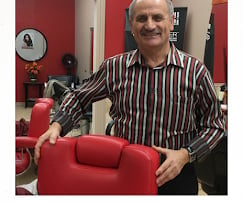 Man in striped shirt holding red cushion in front of red interior background